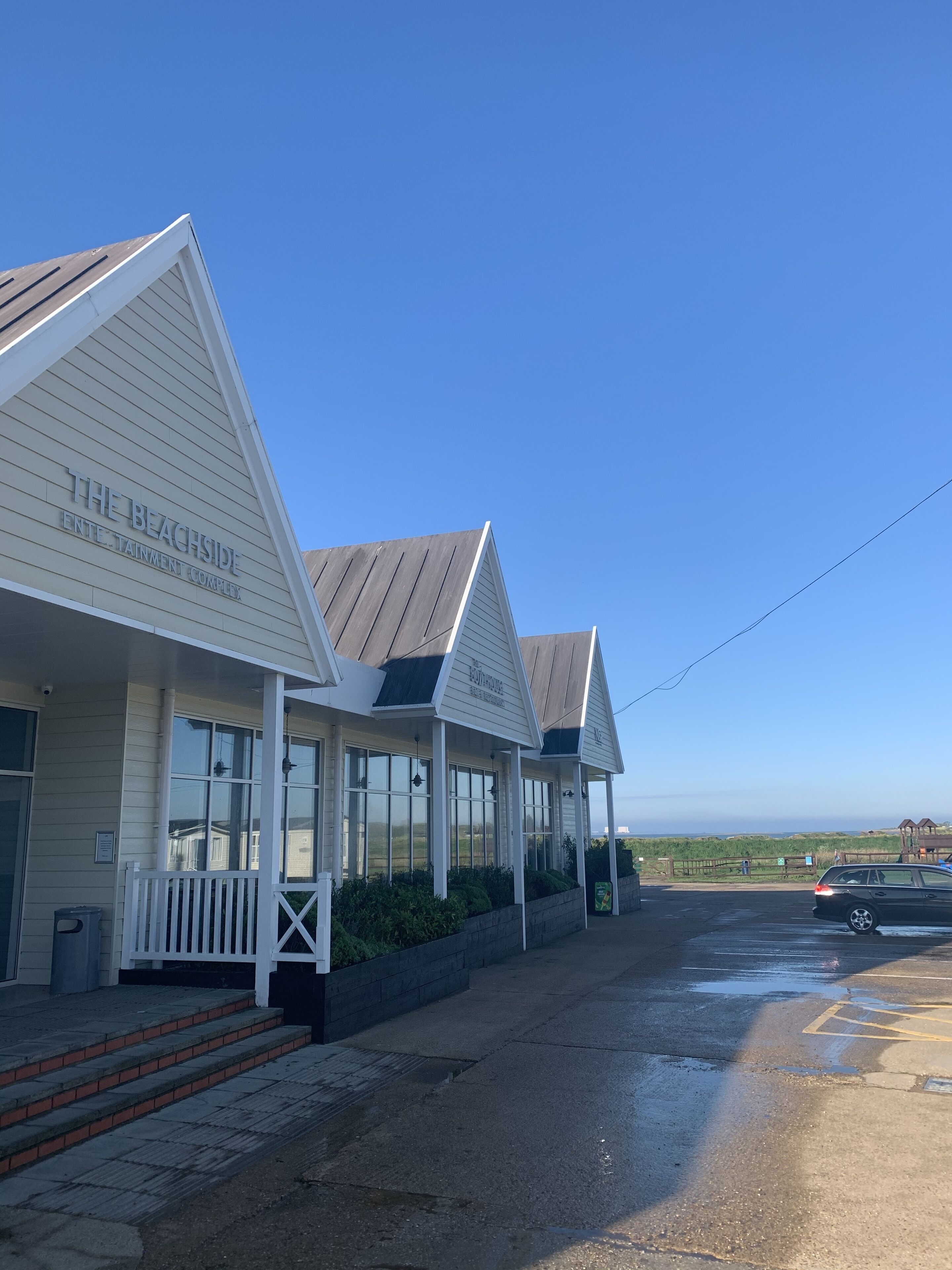 A beachfront building named "The Beachside Entertainment Complex" with a covered entrance and steps leading up to it.