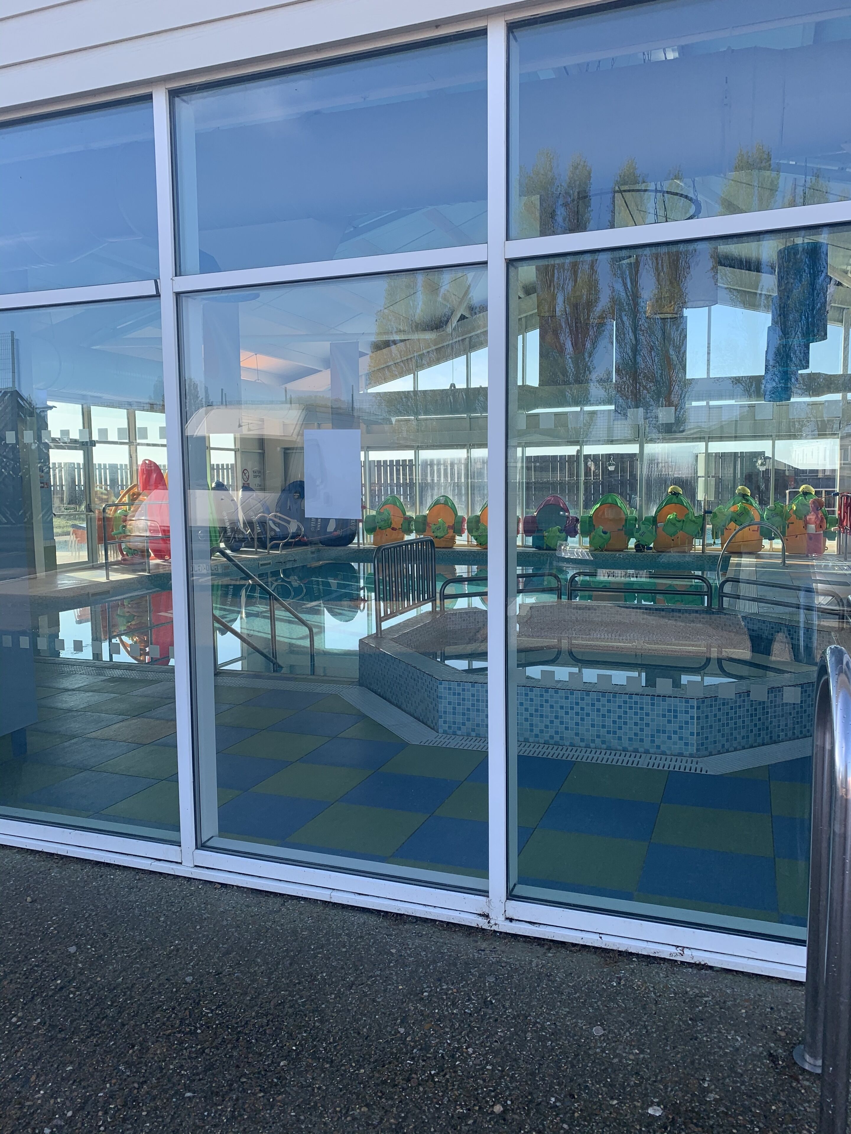 A swimming pool area with a tiled deck and a glass enclosure.