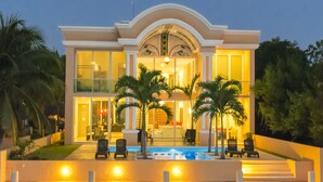 A modern two-story house with a swimming pool, outdoor seating, and palm trees. - Mansion Serenity en Puerto Aventuras (Puerto Aventuras)