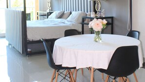 A modern hotel room with a large bed, a dining table with chairs, and a small table with a vase of flowers. - Mansion Serenity en Puerto Aventuras (Puerto Aventuras)