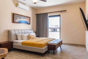 A bedroom with a bed, a nightstand, a bench, a painting, and a window with curtains.