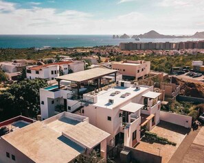 A coastal residential area with modern buildings, a pool, and a view of the sea.