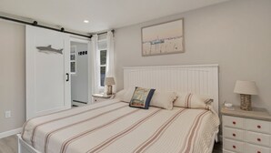 Un dormitorio con cama, mesitas de noche, un armario y un cuadro en la pared.
