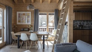 A cozy wooden cabin interior with a dining area, a living room with a sofa, and a kitchen with stone accents. - Bishorn COSY chalet 4 personnes (Les Masses)