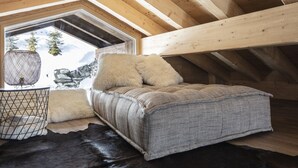 A cozy attic bedroom with a large window, wooden beams, a bed with fluffy pillows, a woven blanket, and a leather rug. - Bishorn COSY chalet 4 personnes (Les Masses)