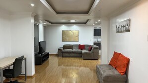 A living room with a sofa, a TV, a dining table, and a kitchen in the background. - Large Private 3 BDR apartment in downtown Quito (Quito)
