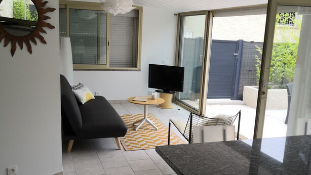 A modern living room with a sofa, a TV, and a dining area with a table and chairs. - Maisonnette with swimming pool access, on the campsite (Aix en Provence)