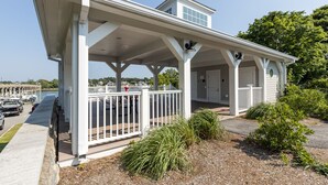 A covered outdoor area with a white railing, a small tower-like structure, and a view of the marina in the background.