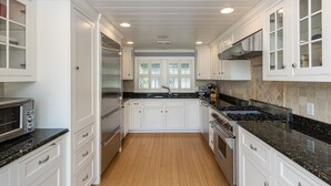 A modern kitchen with white cabinets, a stainless steel refrigerator, a gas stove, and a microwave.
