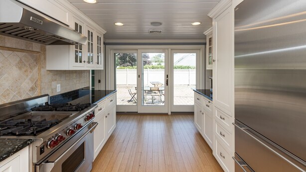 A modern kitchen with stainless steel appliances, white cabinetry, and a view to an outdoor patio area.
