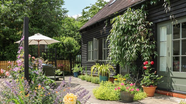 A garden with a wooden house, a bench, and potted plants. - The Barn at Sandhole Cottage (Tonbridge)
