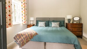 A bedroom with a bed, two nightstands, a dresser, a window with curtains, and a lamp. - The Barn at Sandhole Cottage (Tonbridge)
