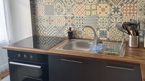 Et moderne køkken med mørke skabe, en stålvask og et mønstret bagpanel.