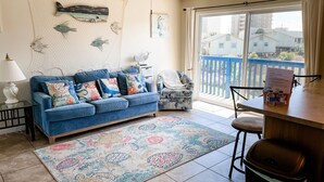 Ein Wohnzimmer mit blauem Sofa, gemustertem Teppich und Deckenventilator.