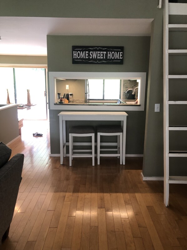 A kitchen area with a 'HOME SWEET HOME' sign, wooden flooring, and a white counter with stools. - 3 bedroom four season condo one mile from Sugarbush (Warren)