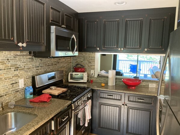 A kitchen with dark cabinets, a microwave, a toaster, a stove, and a sink. - 3 bedroom four season condo one mile from Sugarbush (Warren)