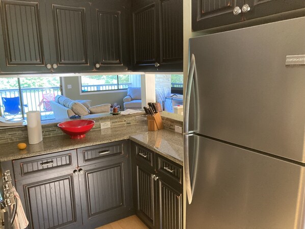 A kitchen with dark wooden cabinets, a stainless steel refrigerator, and a red mixing bowl on the counter. - 3 bedroom four season condo one mile from Sugarbush (Warren)