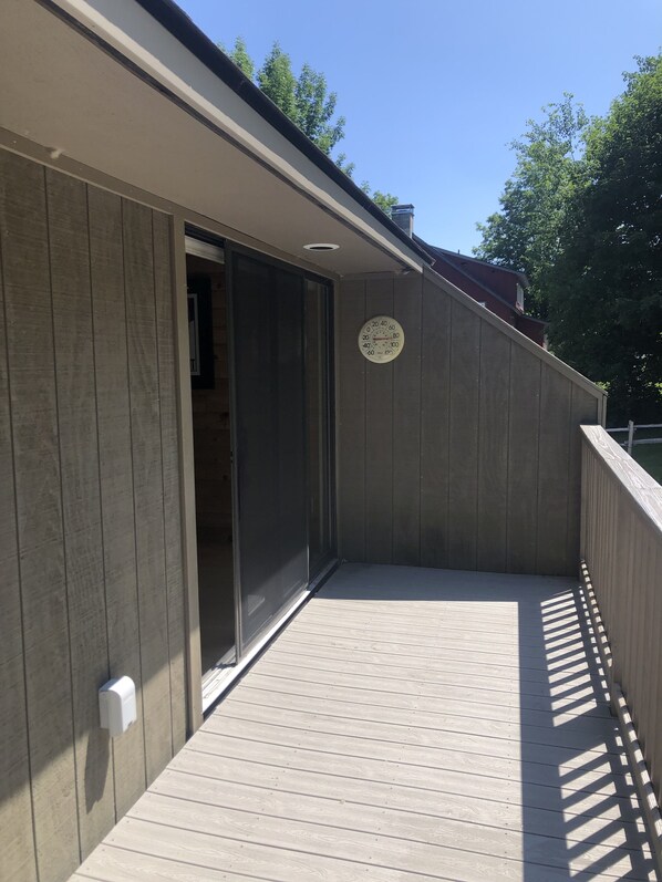 Une terrasse en bois avec une porte-fenêtre coulissante donnant sur un espace intérieur.