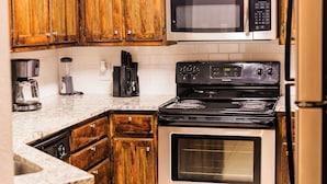Una cocina con gabinetes de madera, estufa de acero inoxidable, microondas y refrigerador.