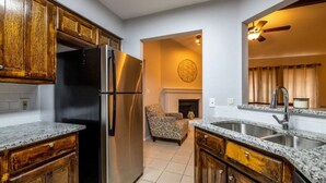 Una cocina con armarios de madera, un refrigerador negro, encimeras de granito y un lavaplatos integrado.
