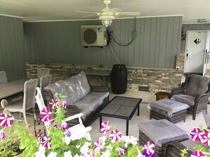 Ein Patio im Freien mit Korbmöbeln, einem Deckenventilator und einer Ziegelwand.