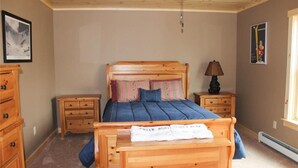 A bedroom with a wooden bed, two nightstands, a dresser, and a ceiling fan. - Ski Retreat with scenic mountian and river views  (Hanover)