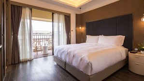 A modern hotel room with a large bed, a bedside table, a nightstand, and a view of a balcony with outdoor furniture. - Wyndham Grand Royal Hotel Jinlin Lijiang (Lijiang)