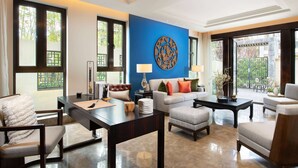 A modern living room with a blue accent wall, a large round decorative piece, and a view through the glass door. - Wyndham Grand Royal Hotel Jinlin Lijiang (Lijiang)