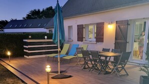 Une terrasse avec des meubles d’extérieur, une table et un parasol bleu.