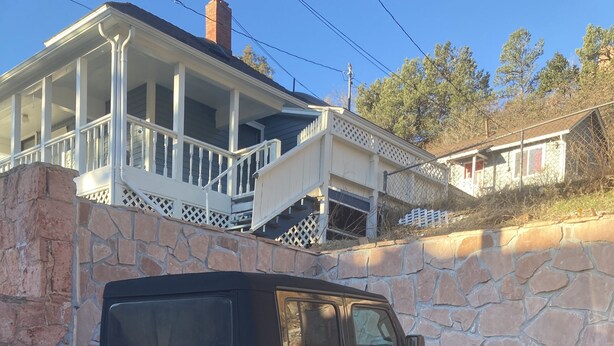Un VUS noir est garé devant un mur de pierre, avec une maison en arrière-plan.
