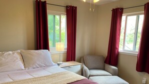 Une chambre à coucher avec un lit, une chaise, une table de chevet et une fenêtre avec des rideaux.