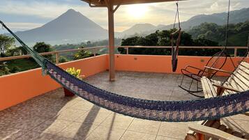 A hammock on a balcony with a view of a mountain.