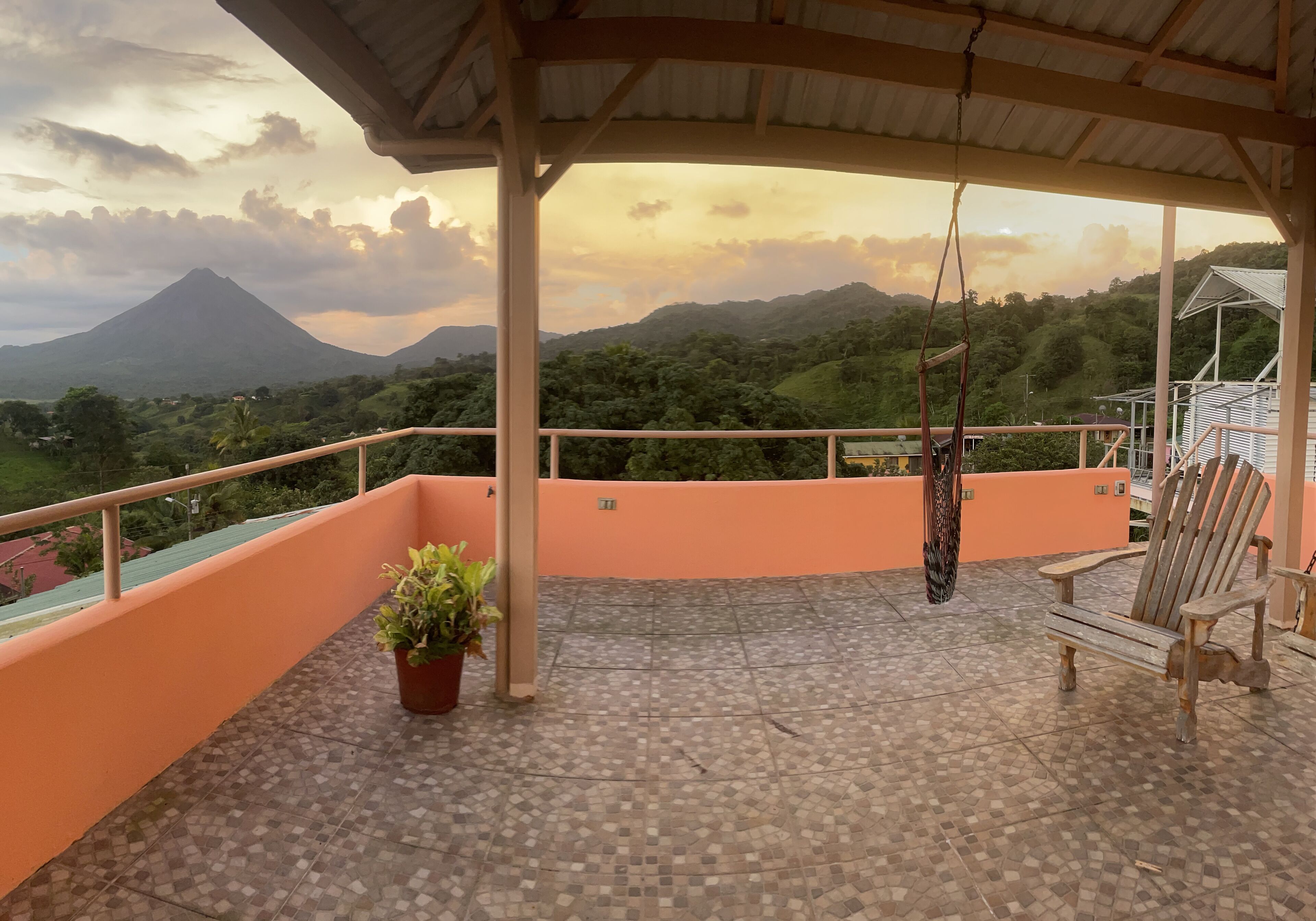 Un balcone con vista su una montagna, una poltrona a dondolo e una panca di legno.