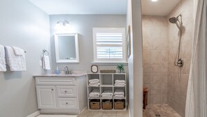 A bathroom with a sink, mirror, towel rack, and a shower area. - Cozy cottage, just a short walk to UofA (Fayetteville)