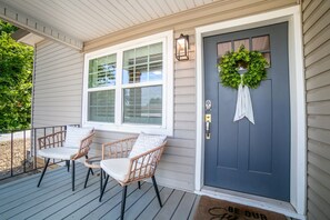A porch with two wicker chairs and a dark-colored door with a wreath. - Cozy cottage, just a short walk to UofA (Fayetteville)