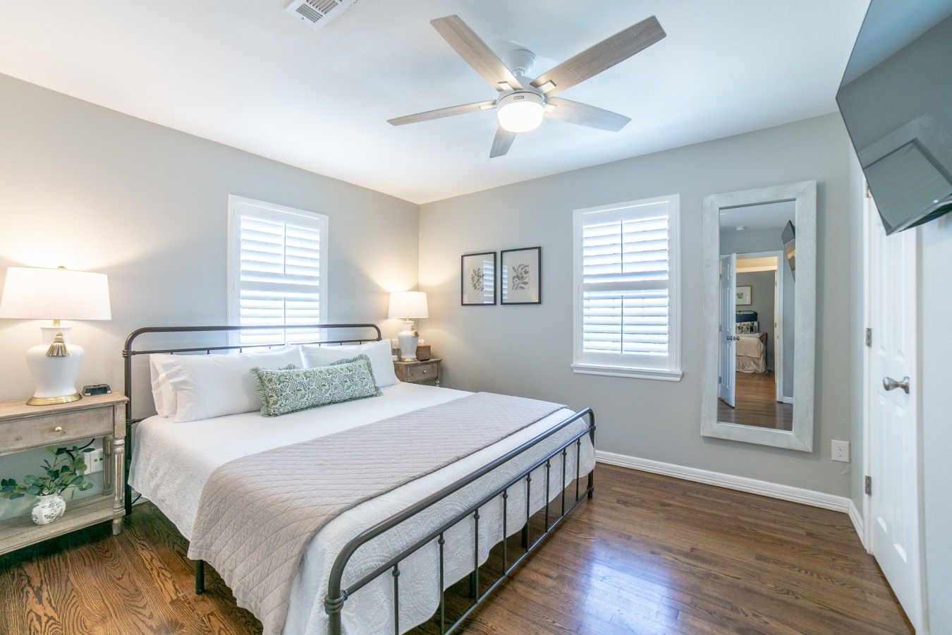 A bedroom with a bed, bedside tables, a ceiling fan, and a mirror.