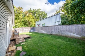 Ein Garten mit Holzterrasse, Grill und einem Kiesweg.