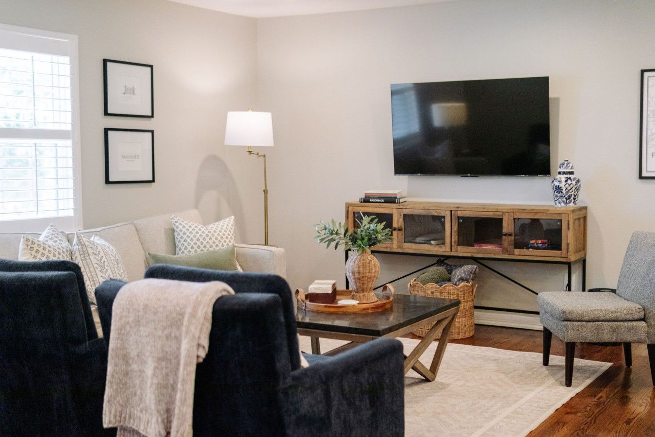 Een woonkamer met een bank, fauteuils, een salontafel, een televisie en een kast.