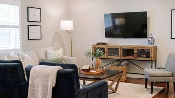 Een woonkamer met een bank, fauteuils, een salontafel, een televisie en een kast.