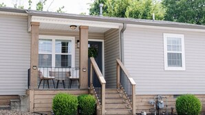 A single-story house with a front porch, a staircase, and a small outdoor seating area. - Cozy cottage, just a short walk to UofA (Fayetteville)