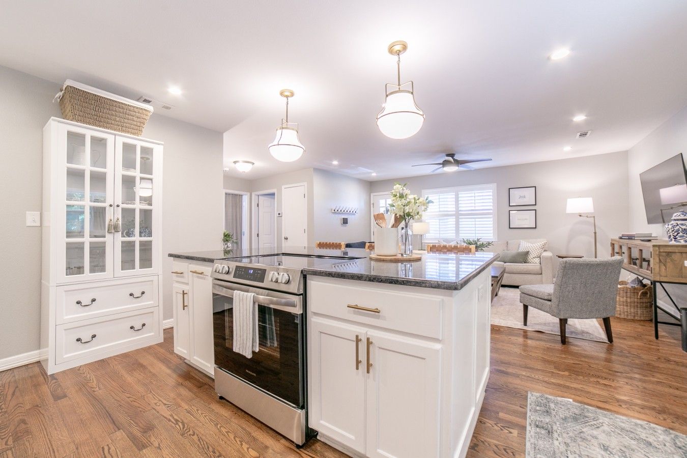 A spacious kitchen with white cabinetry, a central island, and a dining area with a gray chair.