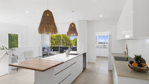 A modern kitchen with a central island, white cabinetry, and pendant lighting. - Sun Crest - amazing ocean views, walk to beach and vibrant village of Woolgoogla (Woolgoolga)