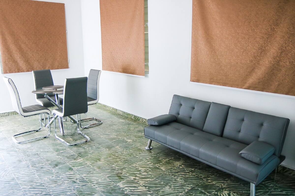 A conference room with a gray sofa, a round table, and four chairs.