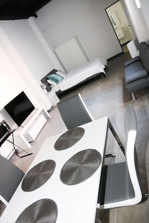 Une chambre d’hôtel moderne équipée d’un lit, d’un canapé, d’une table à manger et d’un téléviseur.