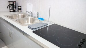 Een moderne keuken met twee roestvrijstalen spoelbakken, een zwart inductiekookplaat en een koffiezetapparaat.