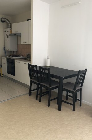 A kitchen with white cabinets, a black table, and four chairs. - Woézon Na Mi (Lyon)