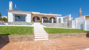 Una casa moderna con fachada de piedra, entrada con tejas y un cielo azul claro.