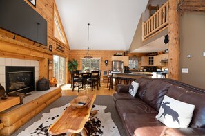 Cozy cabin-style living area with a fireplace, wooden coffee table, and leather sofa.