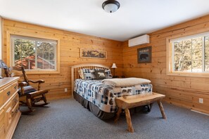 A wooden cabin bedroom with a bed, rocking chair, dresser, and a framed picture of a bear. - Beautiful Terry Peak Cabin, WiFi, hot tub. game room (Lead)