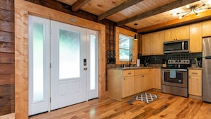 Un interior de madera con cocina que incluye una puerta doble, un microondas, una estufa y un refrigerador.
